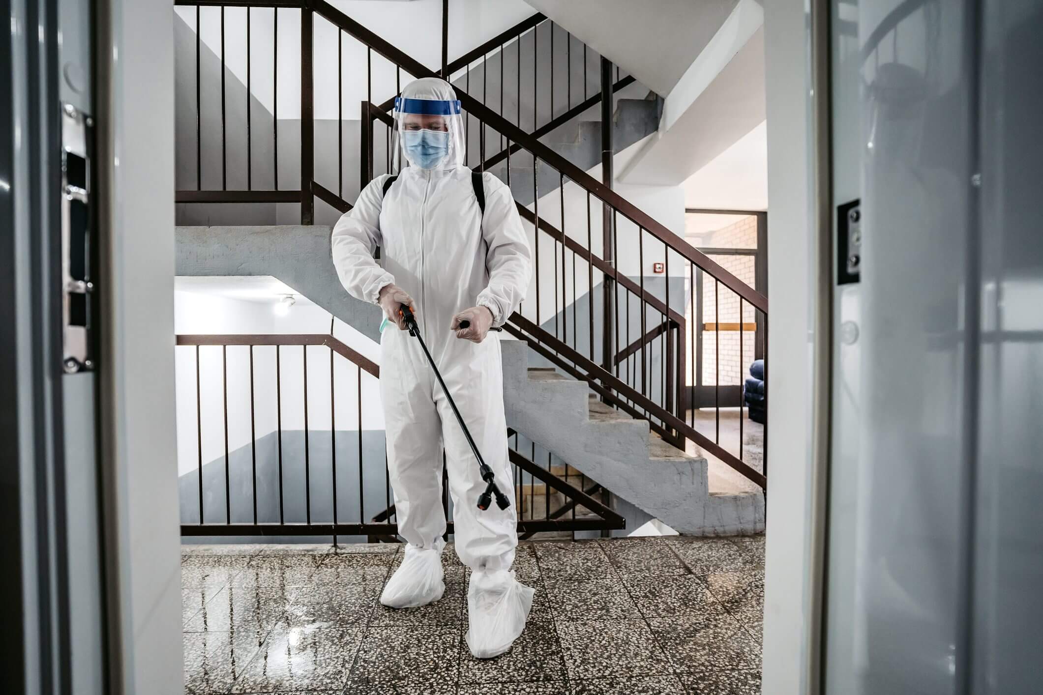 Person in protective suit disinfecting stairwell.