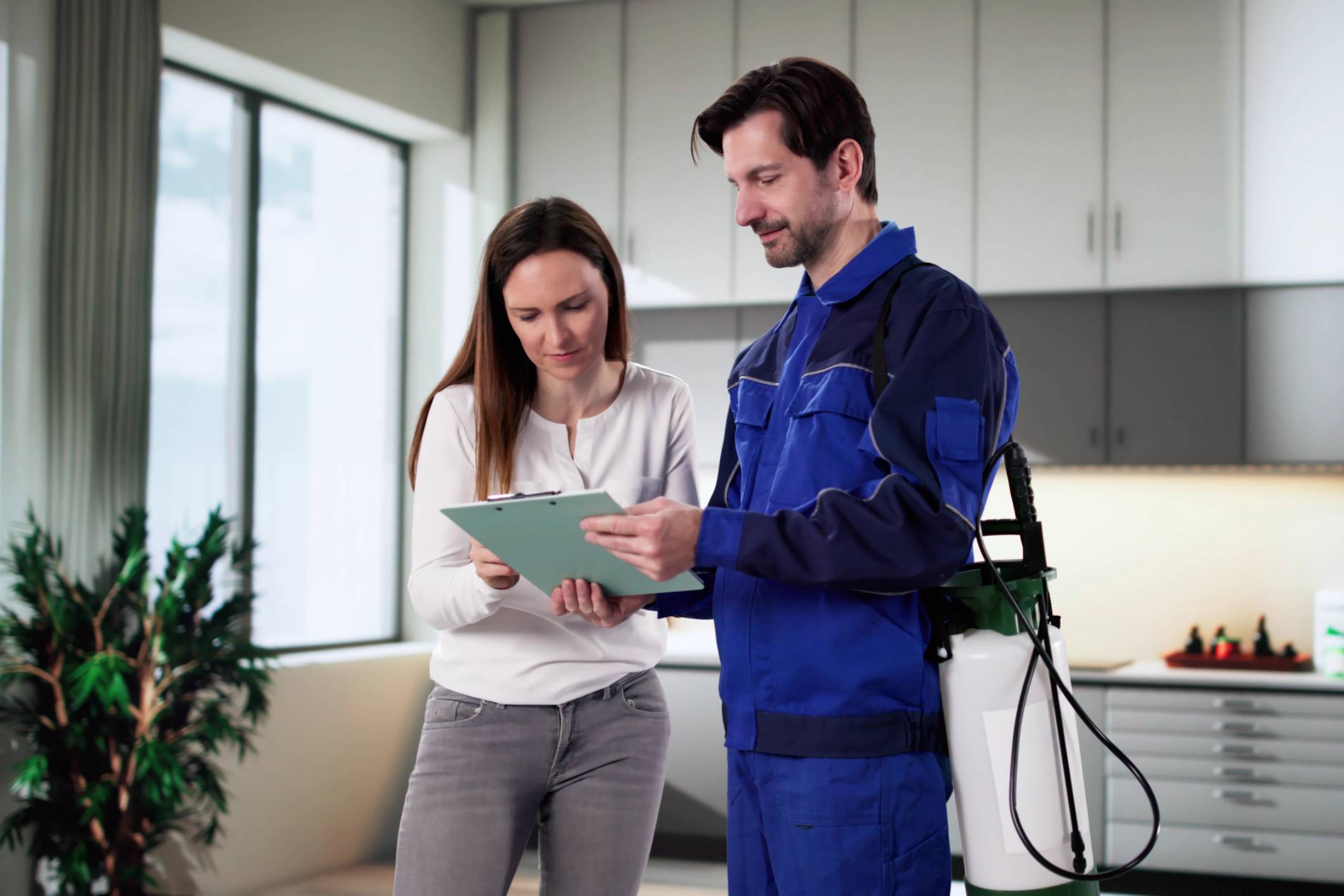 Pest control worker and woman reviewing clipboard.