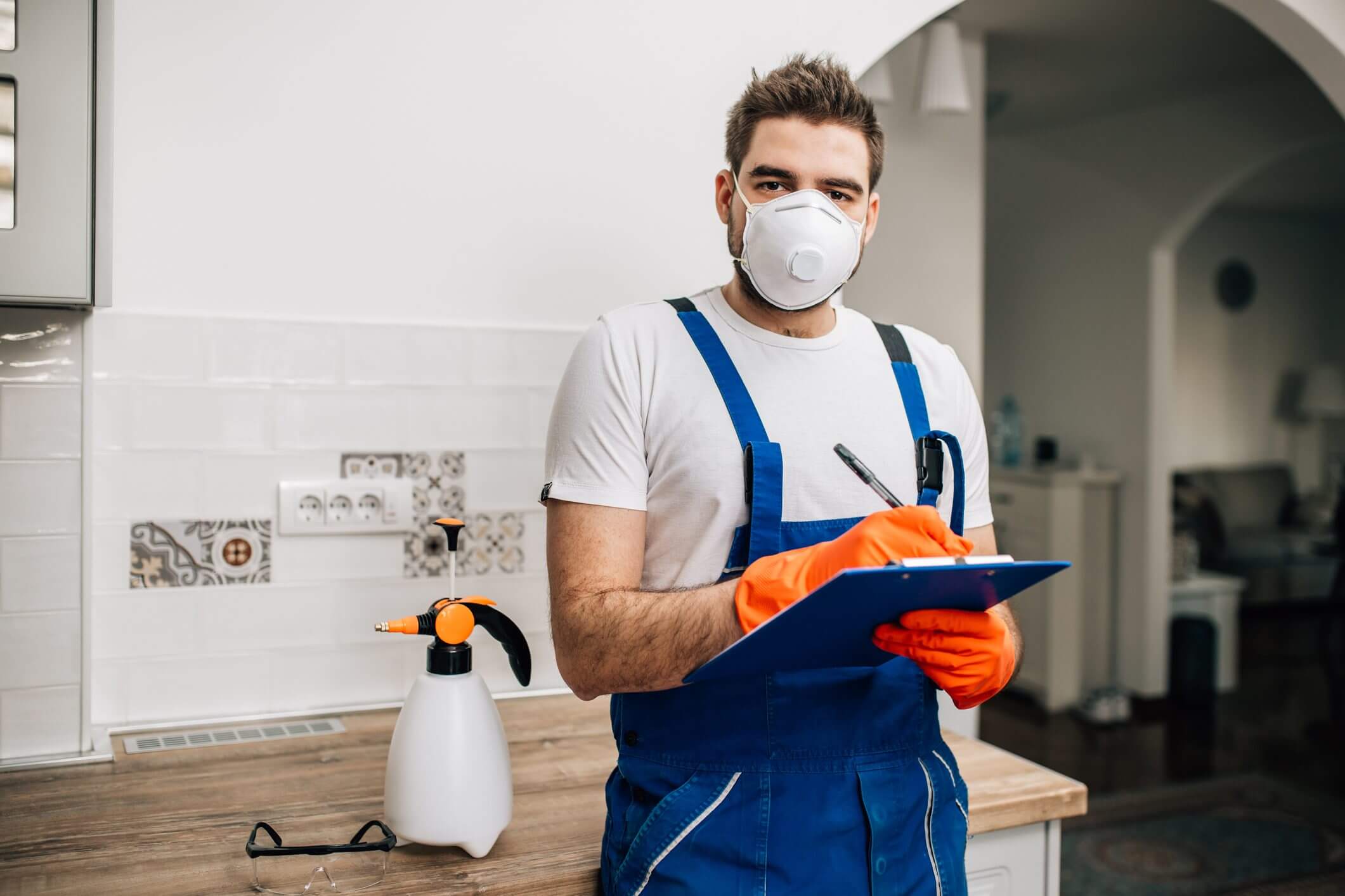 Man in protective gear holding clipboard indoors.